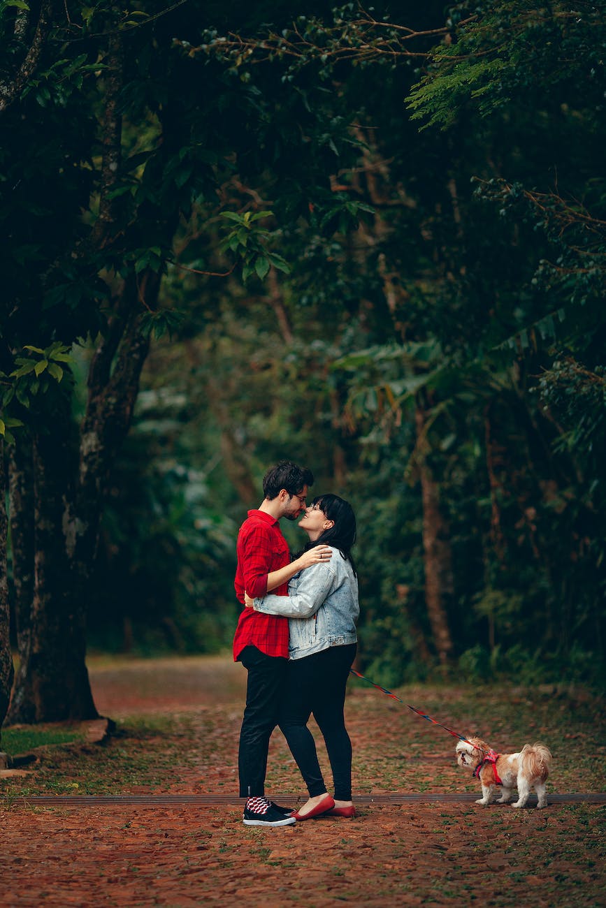 man and woman kissing holding dog with leash