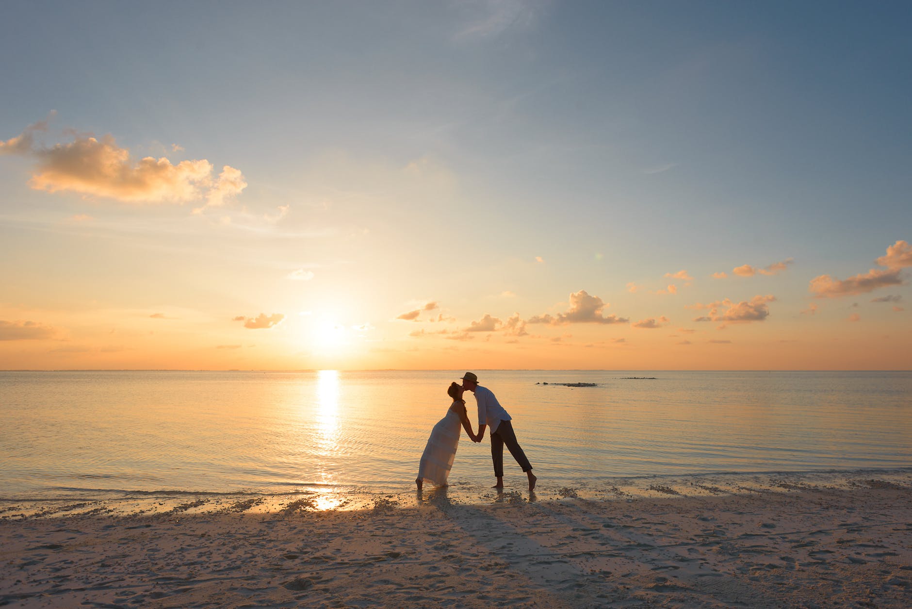 man and woman standing on shore kissing