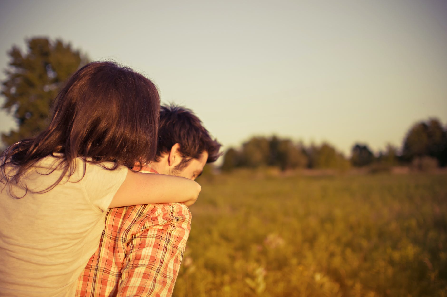man and woman piggy back riding in field